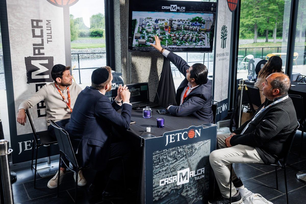 Four advisors around a supplier table as a resort map is presented on screen