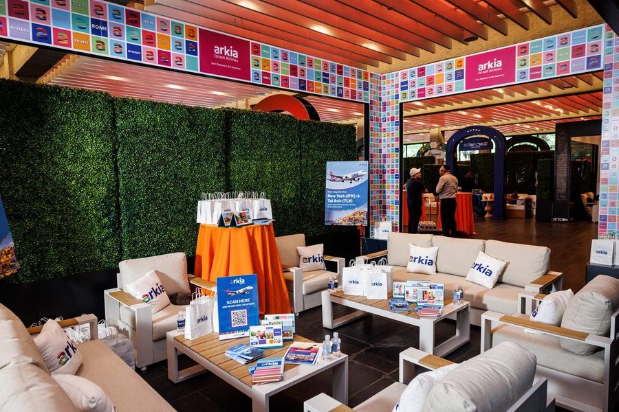 The full Arkia stand — branded structure, couches, lounge chairs and coffee tables
